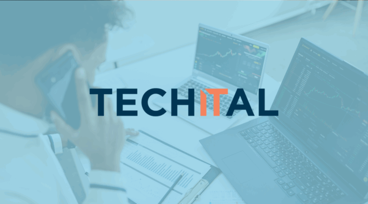 Man on phone looking at clip board and laptops with stock market on his desk with blue Techital overlay